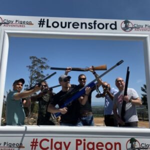 Clay Pigeon Shooting at Lourensford; A shooter aiming a shotgun at a clay target with the scenic Lourensford Estate mountains in the background.